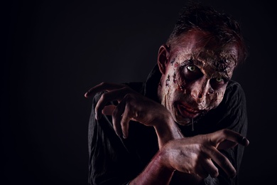 Photo of Scary zombie on dark background, space for text. Halloween monster