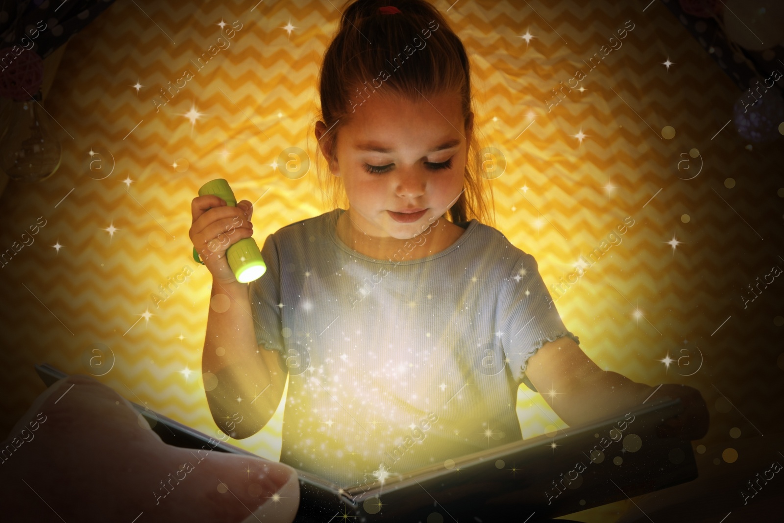 Image of Cute little child reading magic book in play tent