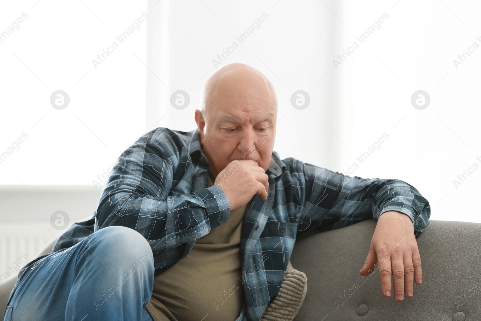 Photo of Depressed senior man sitting on sofa indoors