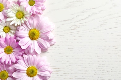 Photo of Beautiful chamomile flowers on wooden background, flat lay with space for text