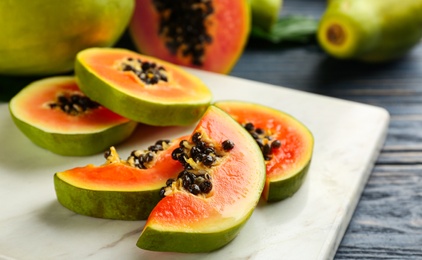 Sliced fresh ripe papaya on white marble board, closeup