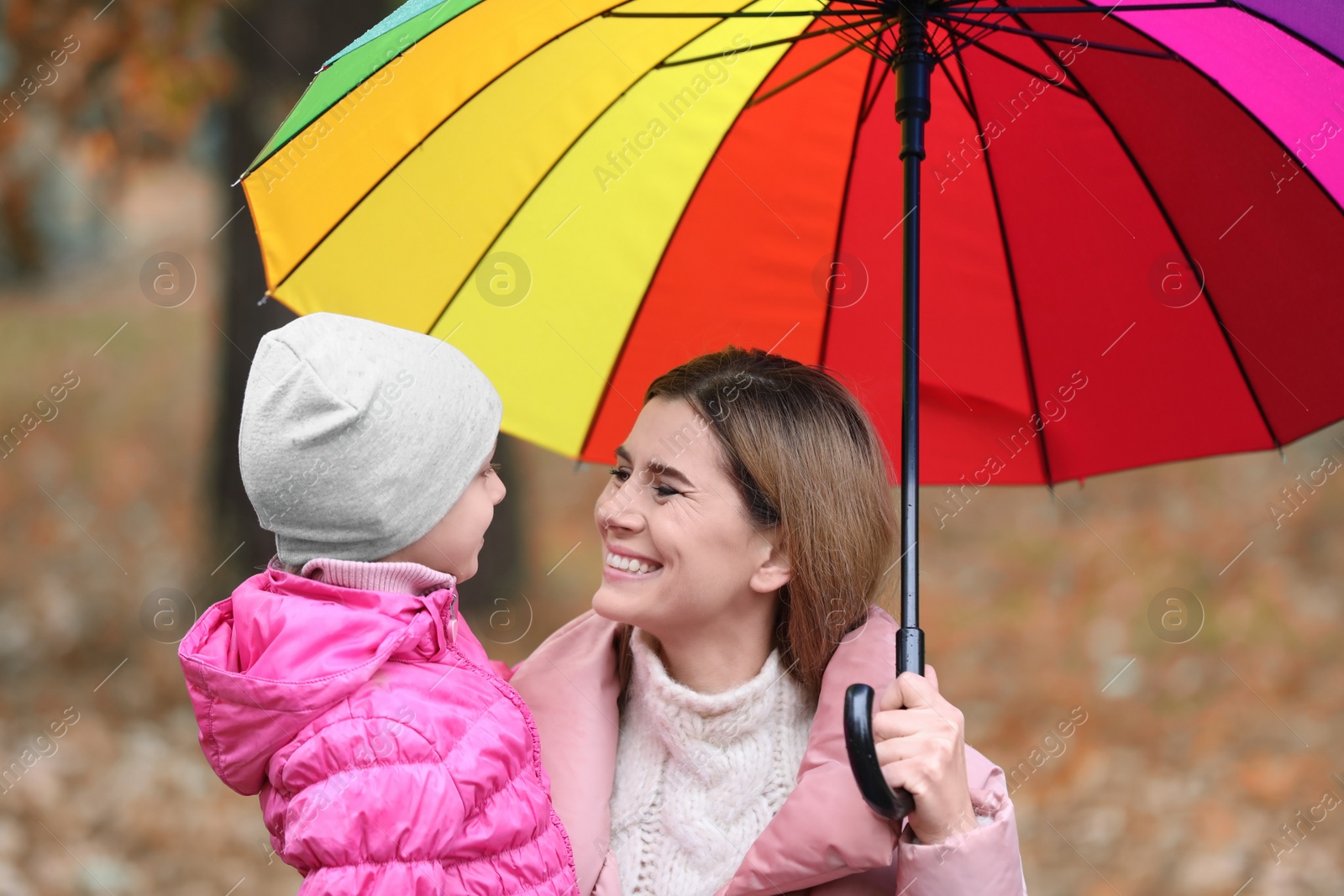 Photo of Mother and daughter with umbrella in autumn park on rainy day