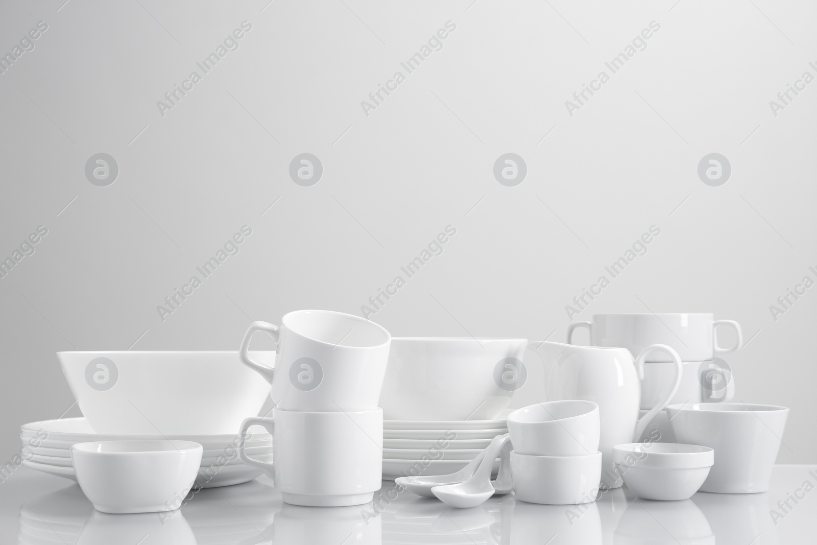 Photo of Set of many clean dishware on light table. Space for text