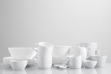 Photo of Set of many clean dishware on light table. Space for text