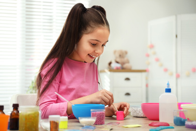 Photo of Cute little girl making homemade slime toy at table indoors