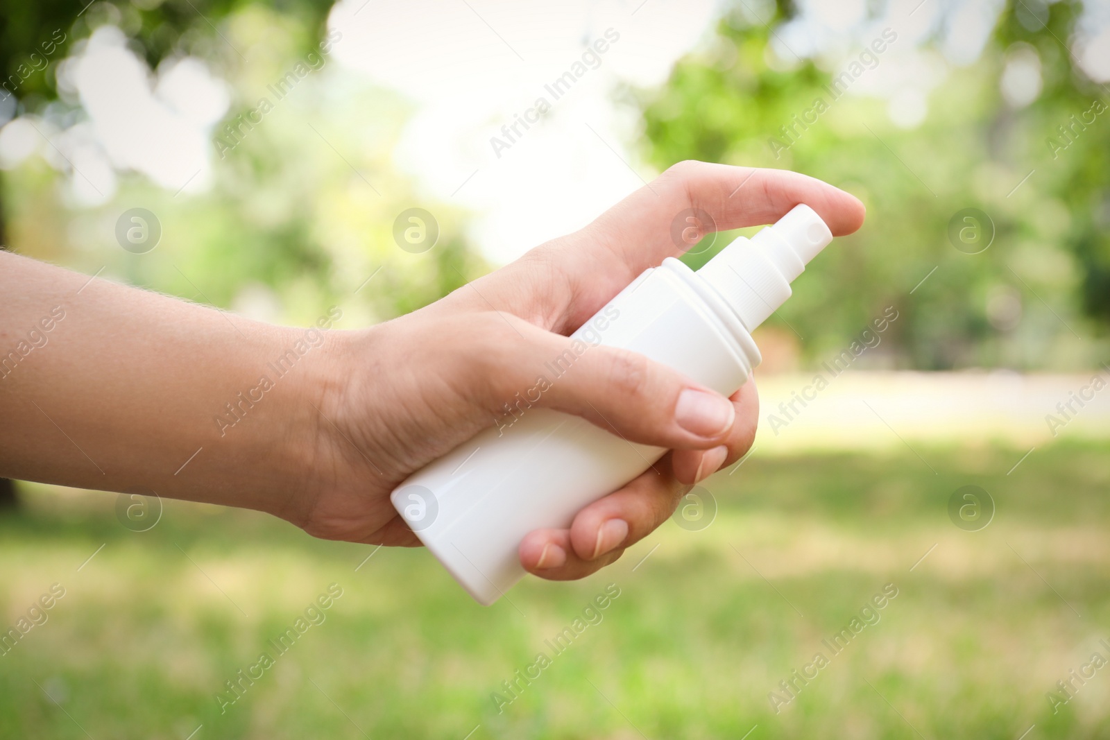 Photo of Woman with bottle of insect repellent spray outdoors, closeup