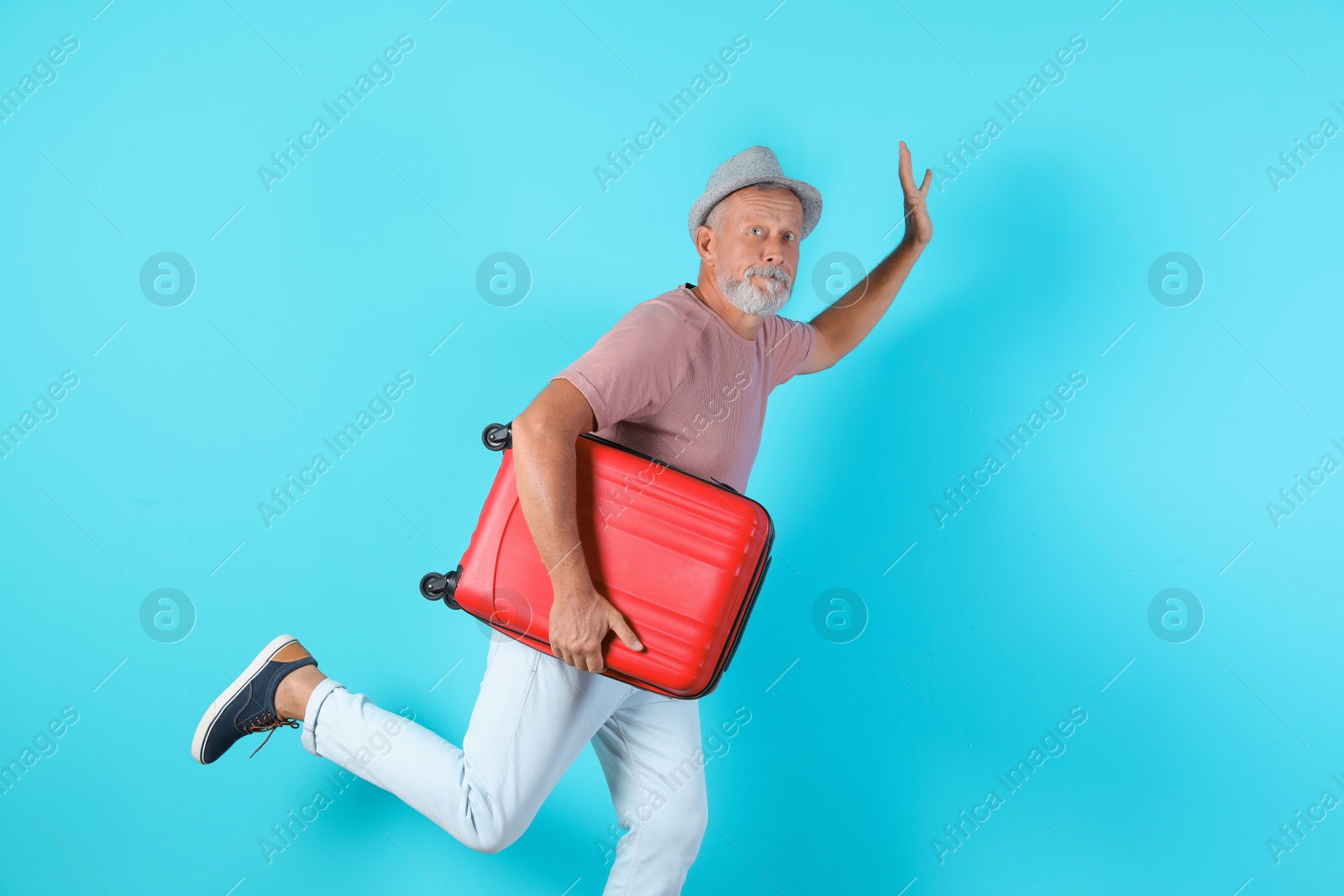 Photo of Senior man with suitcase running on color background. Vacation travel