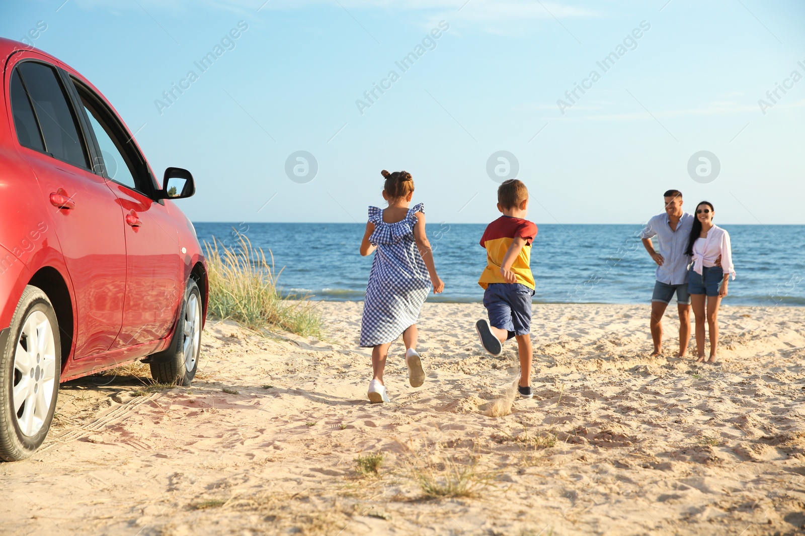 Photo of Little children running to their parents on sandy beach. Summer trip