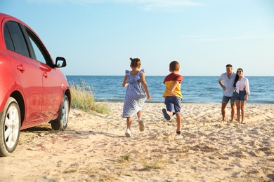 Photo of Little children running to their parents on sandy beach. Summer trip