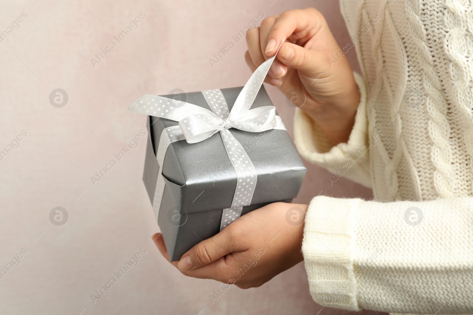 Photo of Woman holding beautiful Christmas gift on light background, closeup