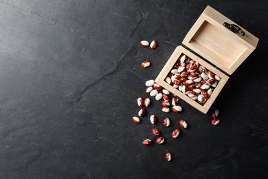 Photo of Wooden box and raw beans on grey background, flat lay with space for text. Vegetable seeds