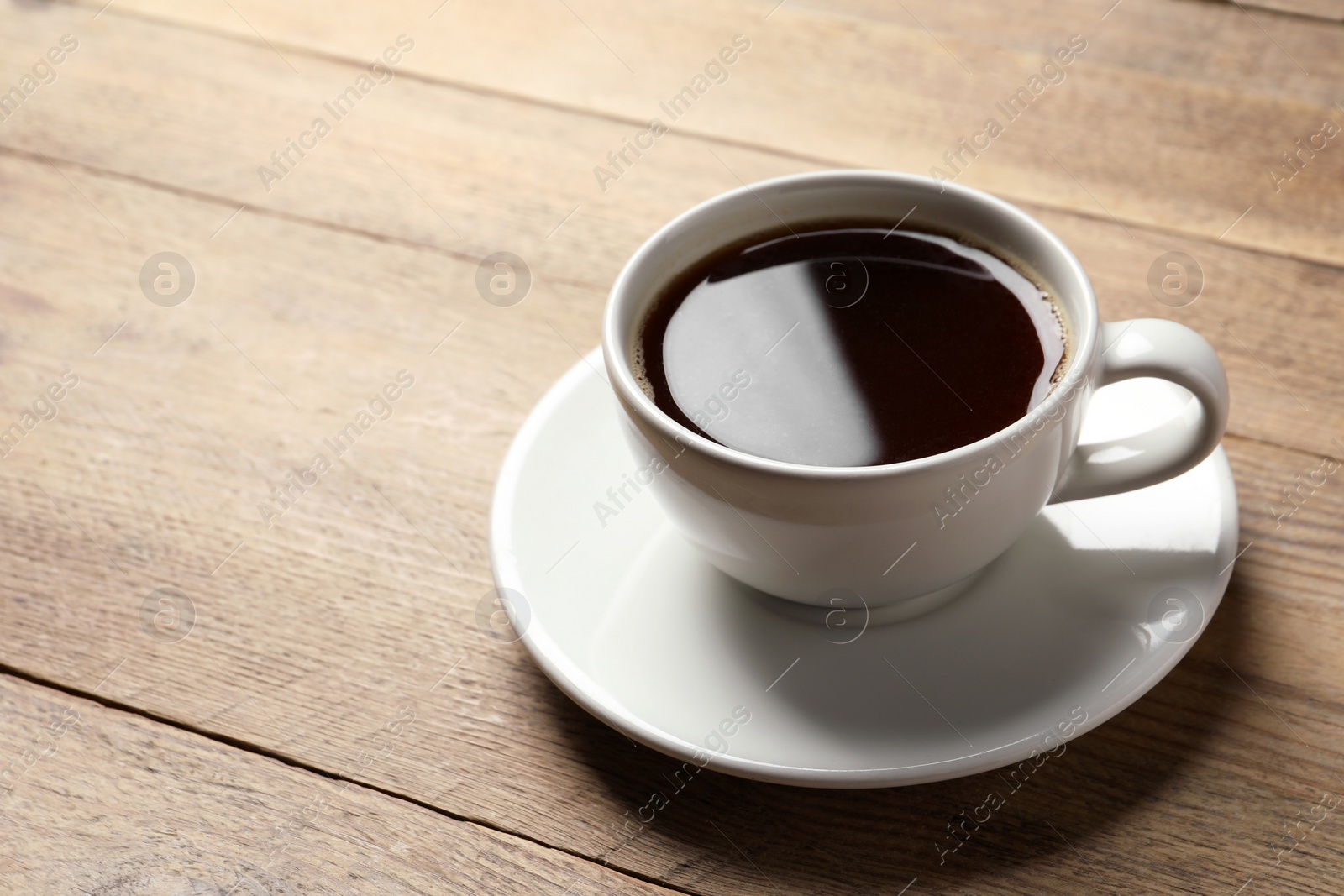 Photo of Cup of aromatic coffee on wooden table. Space for text