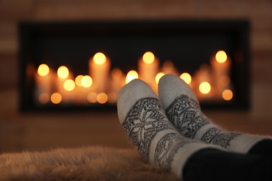 Woman relaxing on fuzzy rug against blurred background, closeup. Winter atmosphere