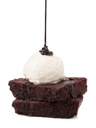 Photo of Pouring chocolate sauce onto delicious brownies with ice cream isolated on white