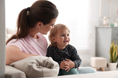 Photo of Mother with her cute little daughter on sofa at home, space for text