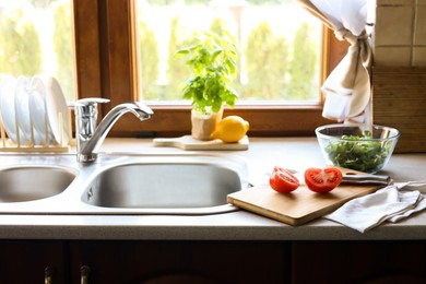 Photo of Cut fresh tomato near sink in kitchen