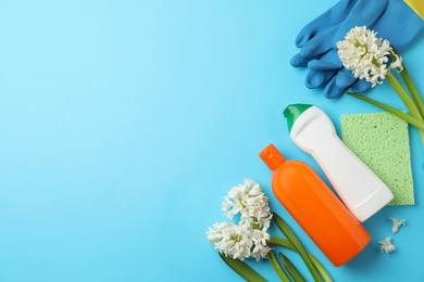 Photo of Composition with spring flowers and cleaning supplies on light blue background, flat lay. Space for text