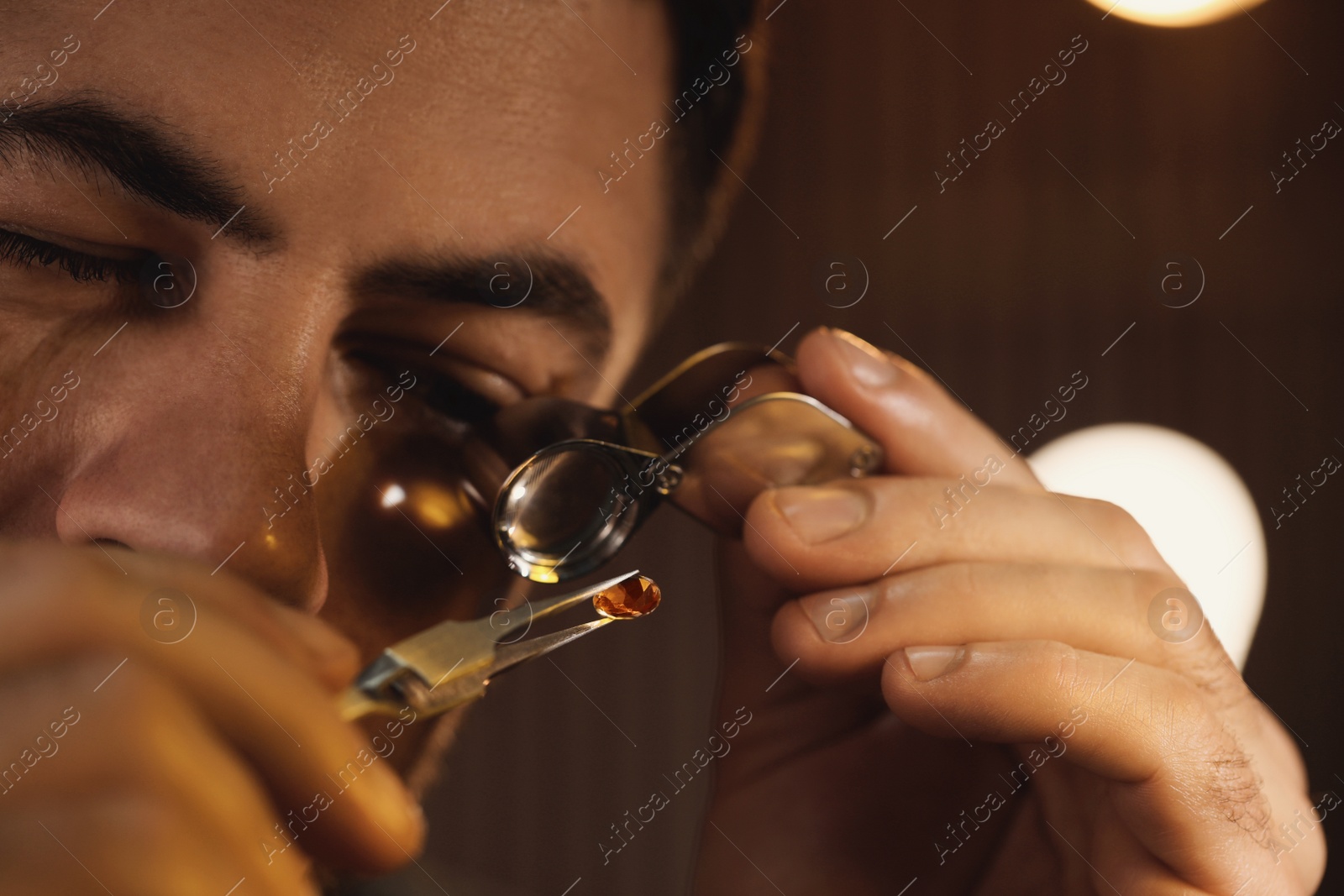 Photo of Jeweler working with gemstone on blurred background, closeup