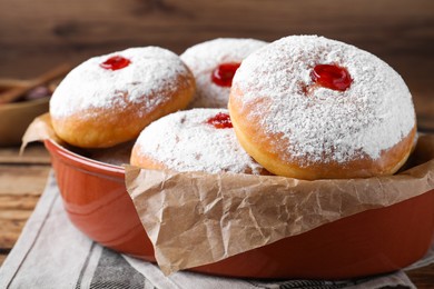 Photo of Delicious donuts with jelly and powdered sugar in baking dish on table, closeup