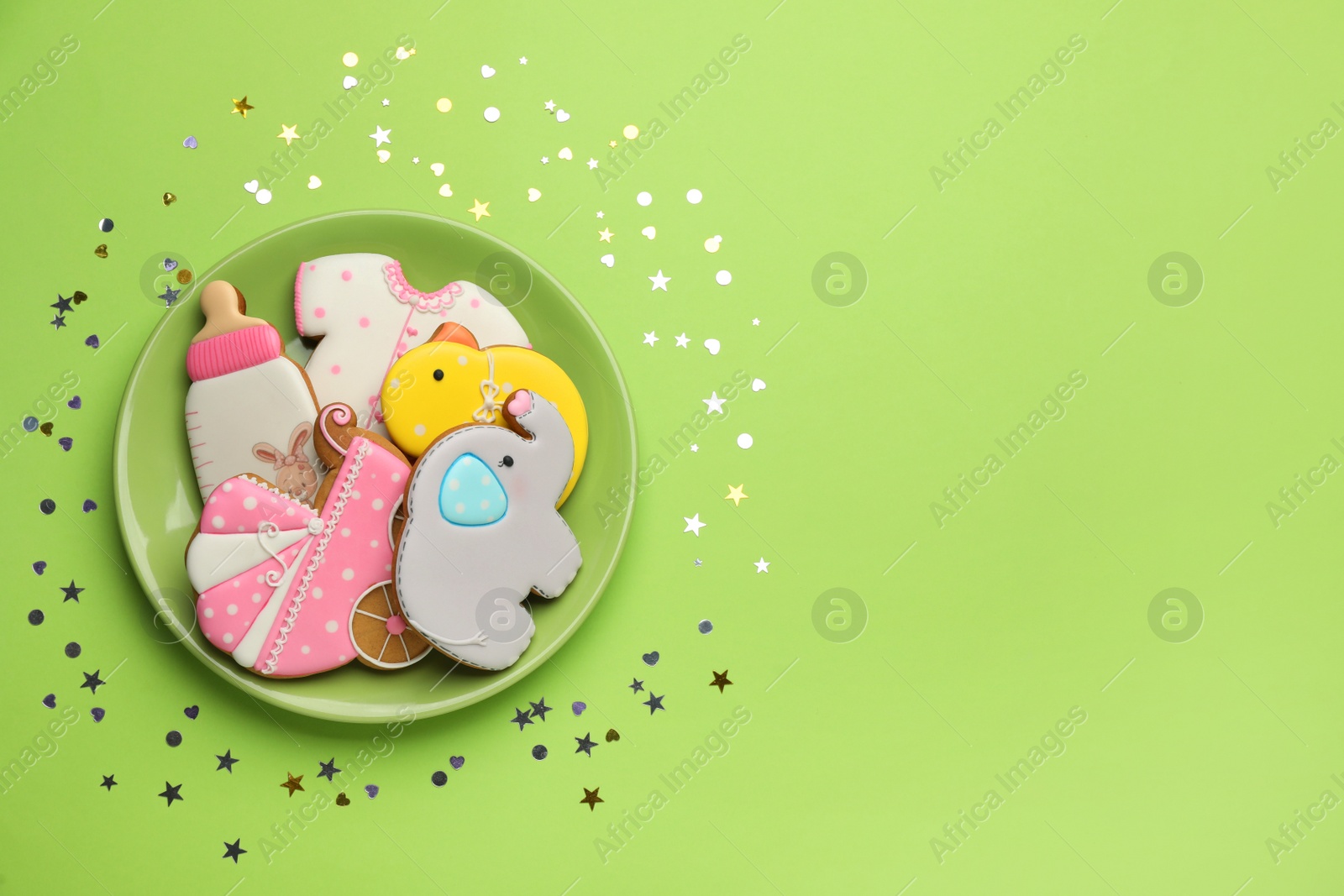 Photo of Plate of baby shower cookies on light green background, flat lay. Space for text