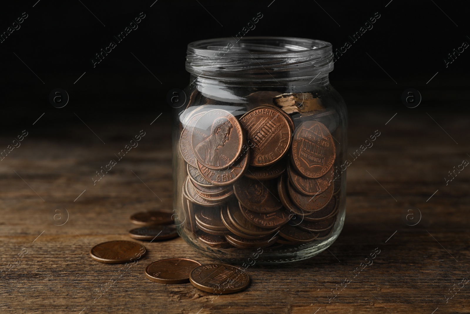 Photo of Glass jar with coins on wooden table