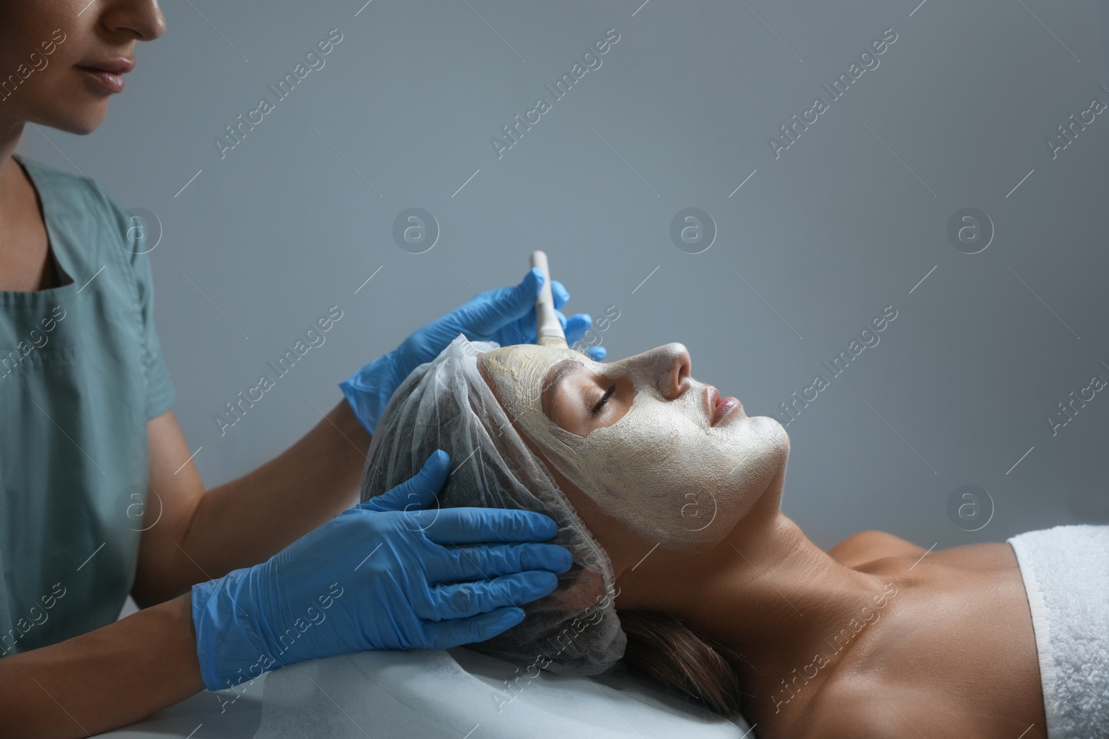 Photo of Cosmetologist applying mask on client's face in spa salon