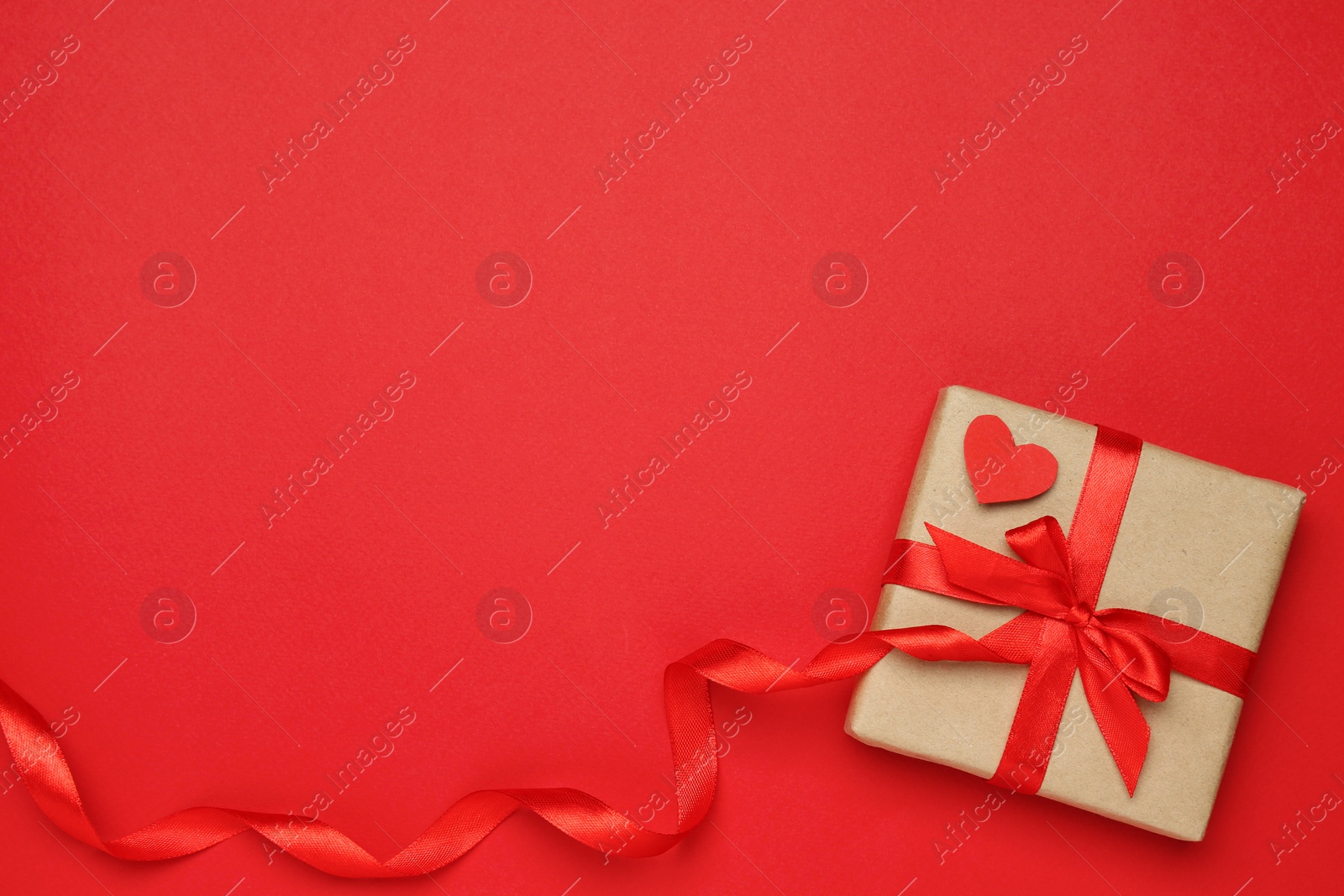 Photo of Beautiful gift box with decorative heart on red background, top view. Space for text