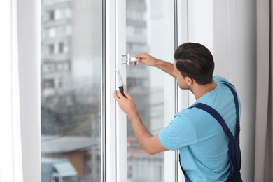 Construction worker repairing plastic window with screwdriver indoors