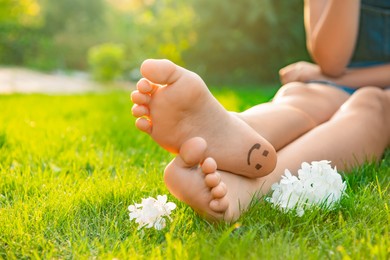 Photo of Teenage girl with beautiful hortensia flowers and smiling face drawn on heel outdoors, closeup. Space for text
