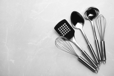 Different kitchen utensils on grey background, top view with space for text