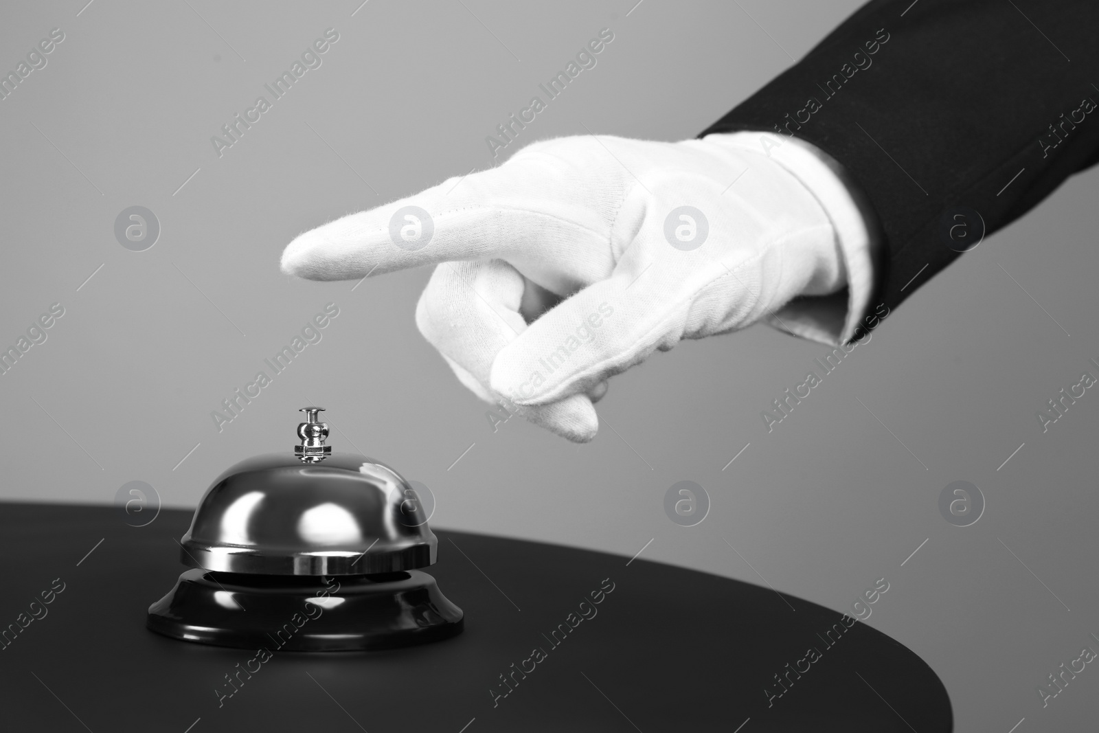 Photo of Butler ringing service bell at table, closeup