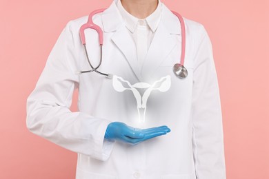 Doctor and illustration of female reproductive system on pink background, closeup