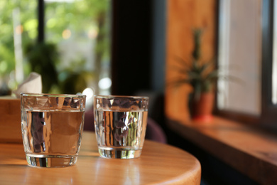 Photo of Glasses of water on wooden table in cafe. Space for text