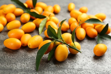 Fresh ripe kumquats and leaves on grey table