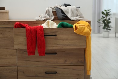 Photo of Cluttered chest of drawers indoors. Clothes in mess