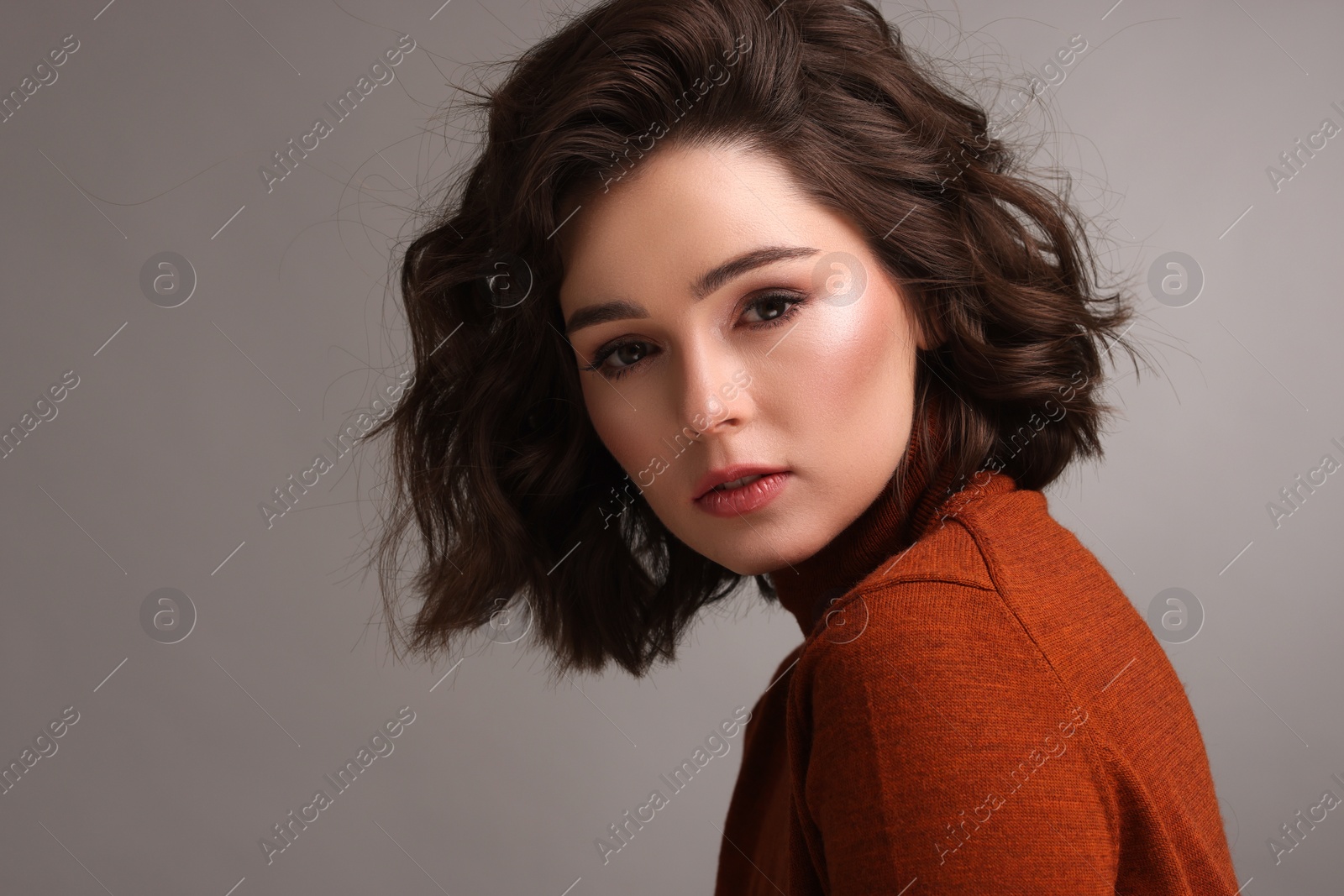 Photo of Portrait of beautiful young woman with wavy hairstyle on grey background. Space for text