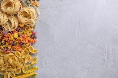 Photo of Different types of pasta on light grey table, flat lay. Space for text