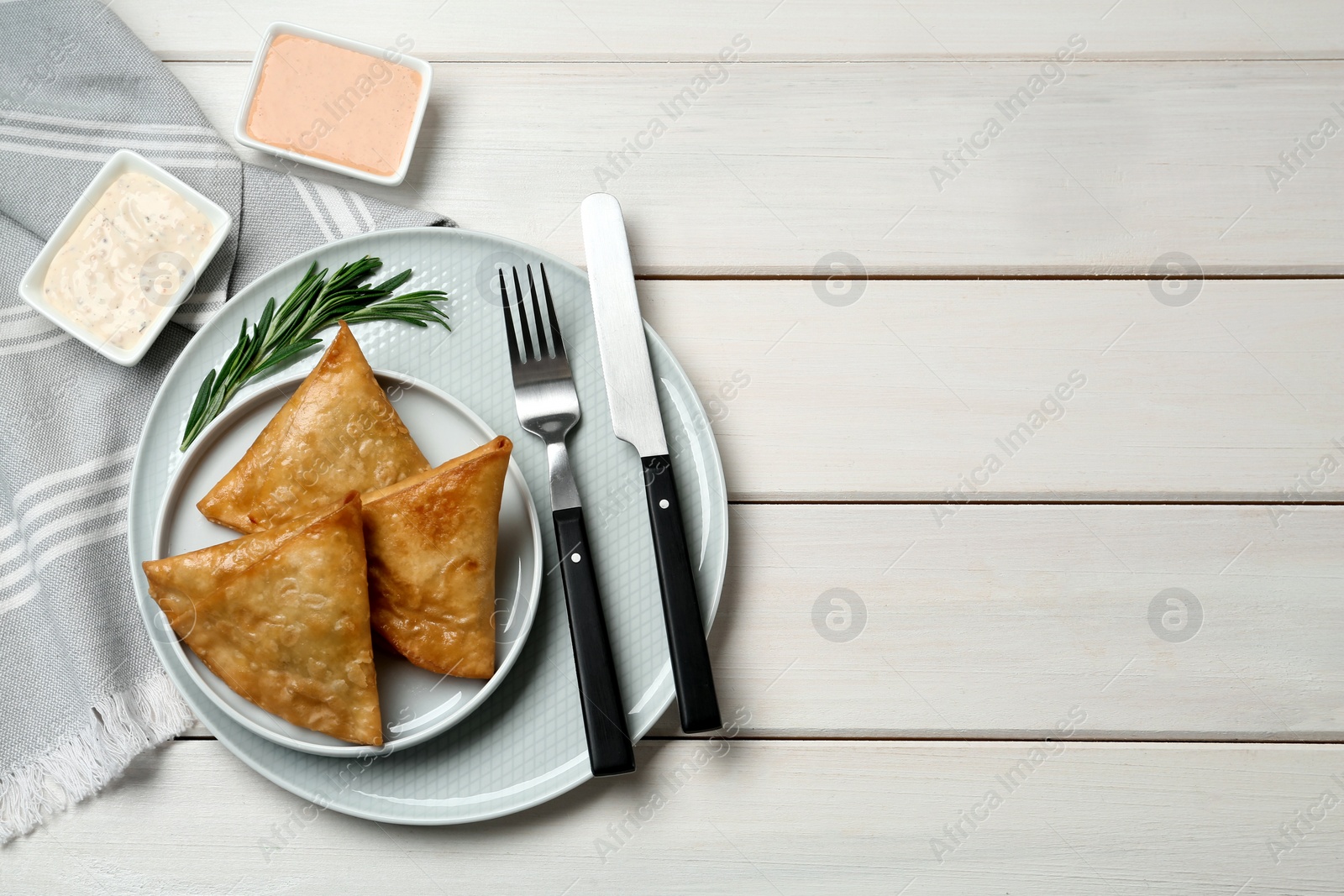 Photo of Fresh delicious crispy samosas served on white  wooden table, flat lay. Space for text