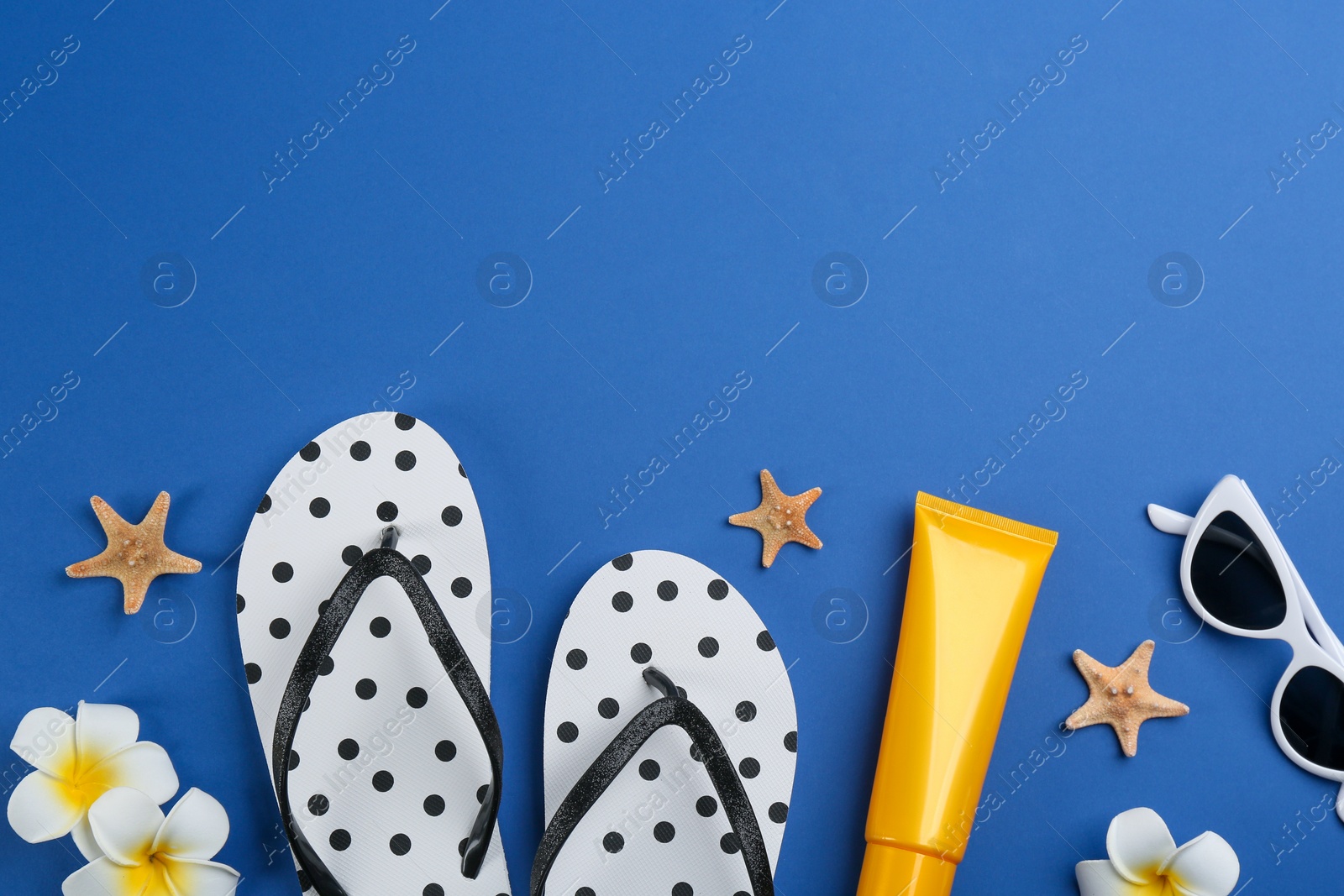 Photo of Flat lay composition with flip flops and beach accessories on blue background. Space for text