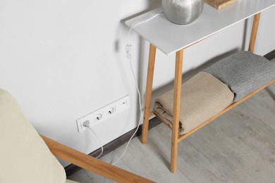 Photo of Electric power outlet sockets and plug on white wall indoors