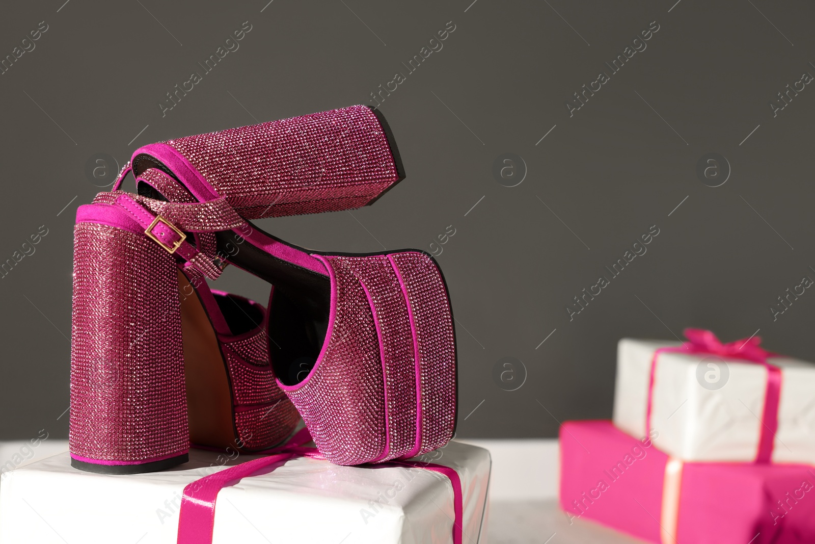 Photo of Stylish presentation of pink high heeled shoes with platform and square toes on gift box indoors. Space for text