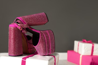 Photo of Stylish presentation of pink high heeled shoes with platform and square toes on gift box indoors. Space for text