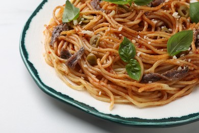 Delicious pasta with anchovies, tomato sauce and basil on white table, closeup