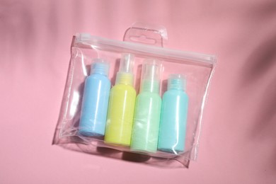 Cosmetic travel kit in plastic bag on pink background, top view. Bath accessories