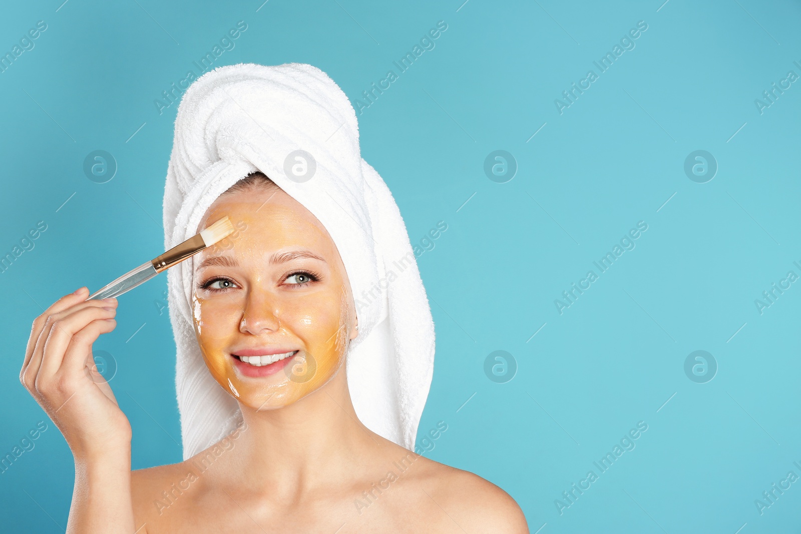 Photo of Beautiful woman applying natural mask on her face against color background. Space for text