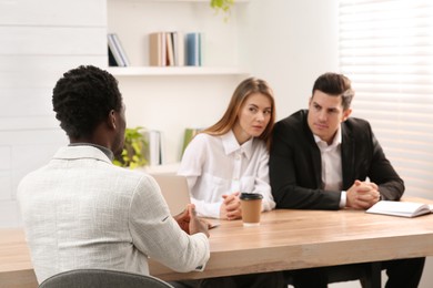 Photo of Coworkers conducting job interview with African American man in office. Racism concept