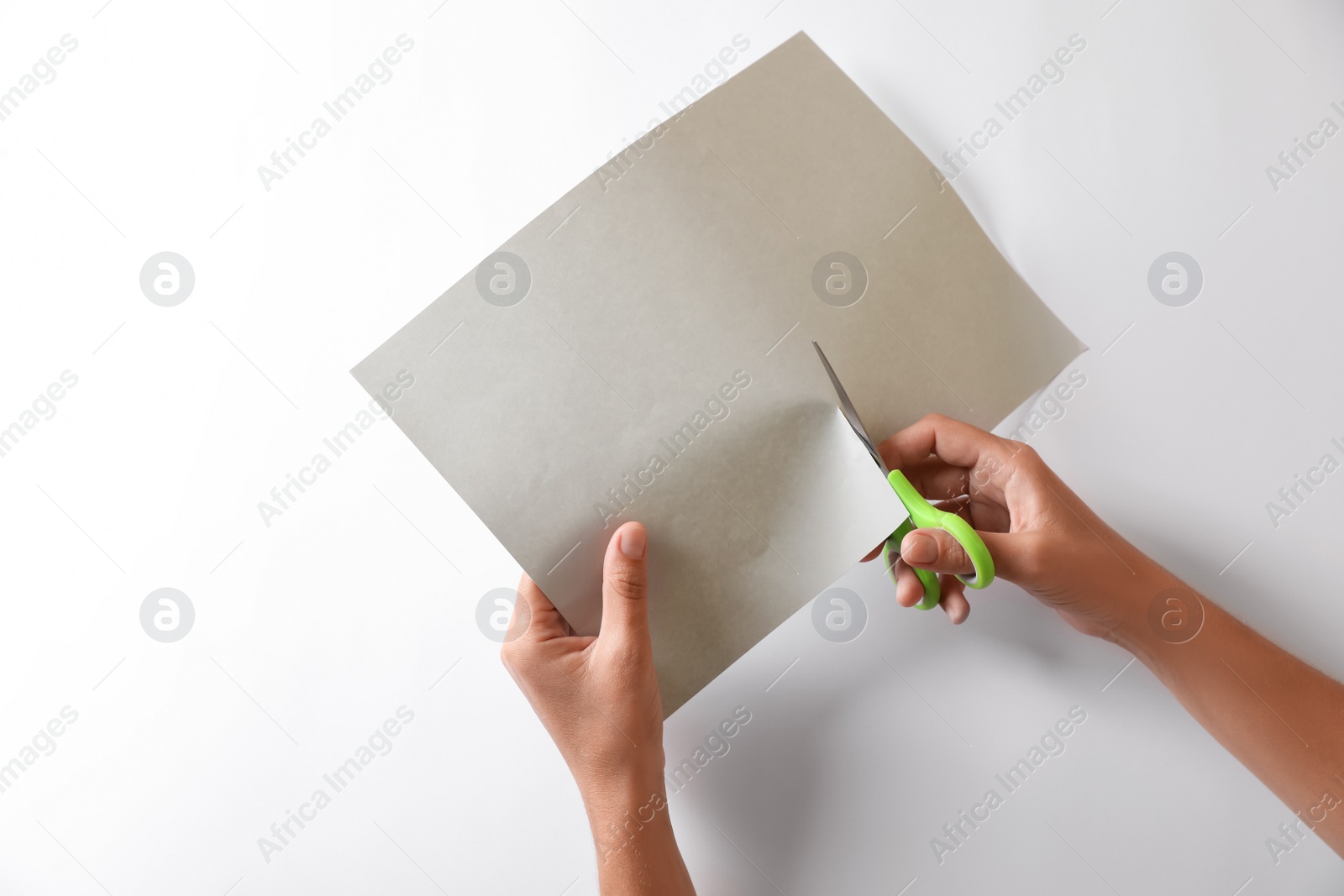 Photo of Woman cutting paper with scissors on white background, top view