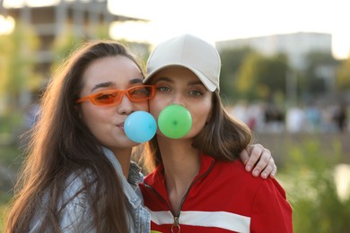 Beautiful young women blowing bubble gums outdoors
