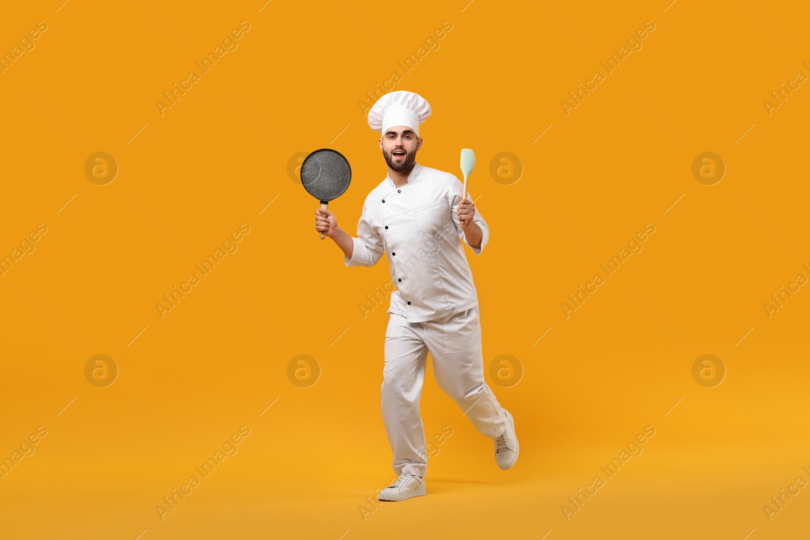 Photo of Professional chef with pan and spatula having fun on yellow background