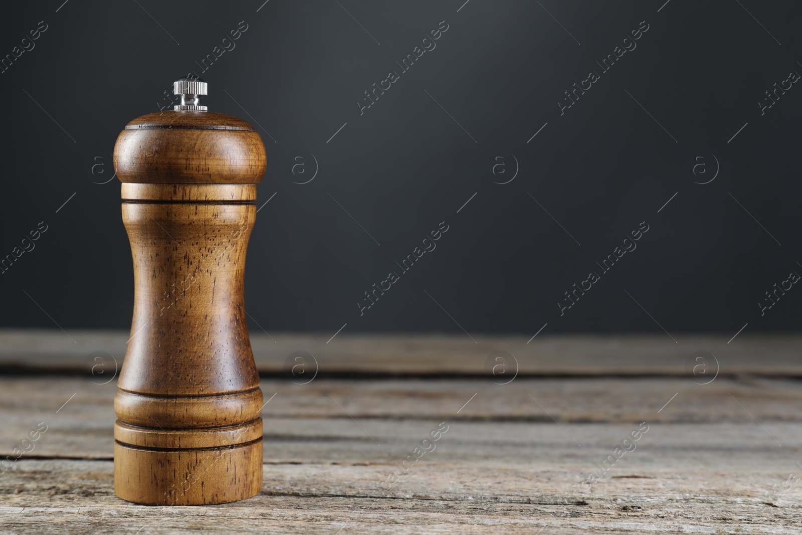 Photo of Salt or pepper shaker on wooden table, closeup. Space for text